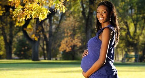 Pregnant woman poses in a park.
